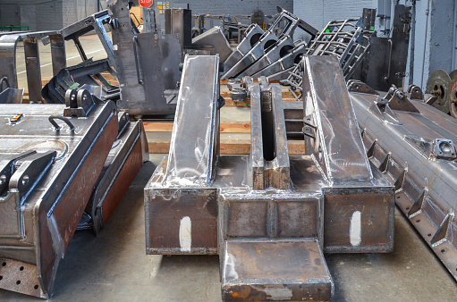 Preparation of welded parts for assembly of crawler dozers and wheel loaders. Storage station spare parts before painting components. Crawler bulldozer assembly line. Heavy industry. Construction equipment.