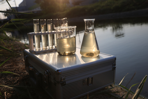 Close-up scientist  sample waste water into flask for laboratory water analysis, industrial and environmental concept