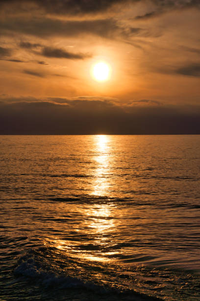 istock Sunset, illuminated sea. A few clouds in the sky, light waves rolling onto the beach 2149210013