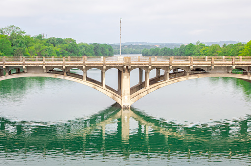 Old bridge reflection over Lady Bird Lake in Austin Texas on a cloudy day