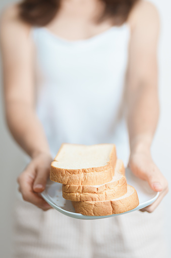 Bread eating and Daily Routine concept. Young woman Hand holding sliced whole grain bread in the morning at home