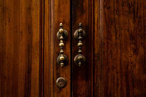 Old brown wooden door with antique handles, detail of a door