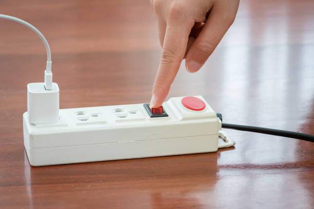 istock Close-up of electrician's hand using red push button to turn on the power strip,Save electricity by turning off the human finger on the red button on the electrical plug. 2149212721