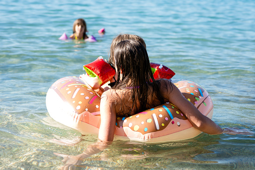 Girls whit inflatable ring enjoying in sea at summer
