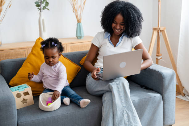 istock Young mother multitasking on sofa with toddler 2149214117