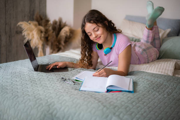 istock Teenage girl doing homework on bed 2149215207