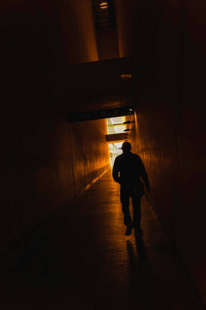 istock A man walks down a dark hallway with a light shining in front of him 2149216106