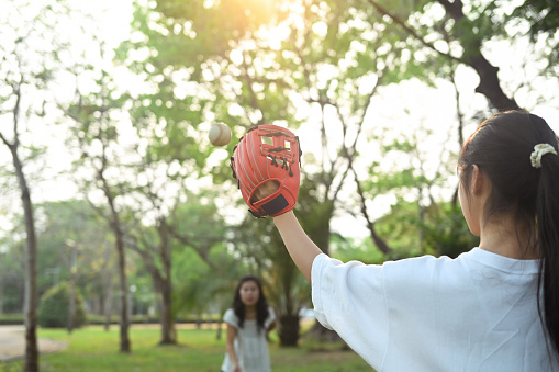 Mother and teenage daughter playing in baseball in the park. Family, sports and leisure activity concept.