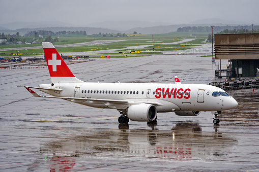 Swiss airplane Airbus A220-100 HB-JBH taxiing to gate of Terminal A at Swiss airport Zürich Kloten on a rainy spring evening. Photo taken April 9th, 2024, Zurich, Switzerland.