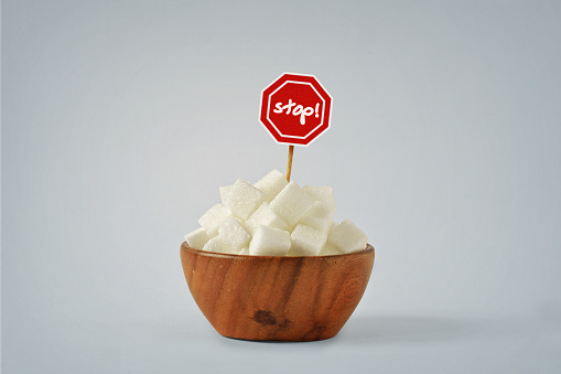 White sugar cubes in wooden bowl with Stop Sign - No sugar diet concept