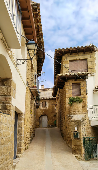A narrow alleyway with rustic houses on either side. The street is lined with buildings and has a stone walkway