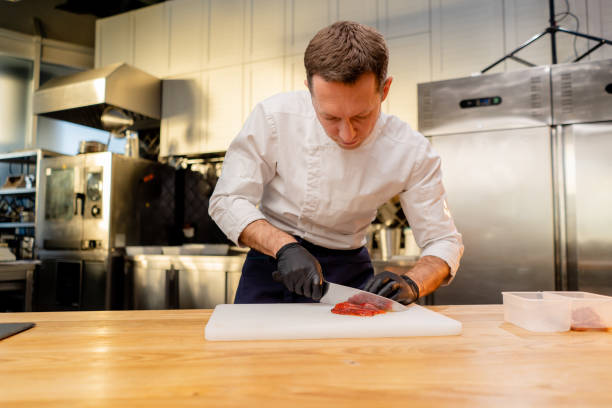 istock chef in a white uniform wearing black gloves cuts bell peppers in the kitchen 2149219016