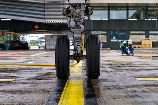 Close-up of front wheel of passenger airplane parked at Swiss airport Zürich Kloten with yellow charging cable on a rainy spring day. Photo taken April 9th, 2024, Kloten, Switzerland.