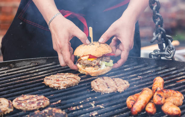 Male hands holding a delicious greasy hamburger with a patty and pickles