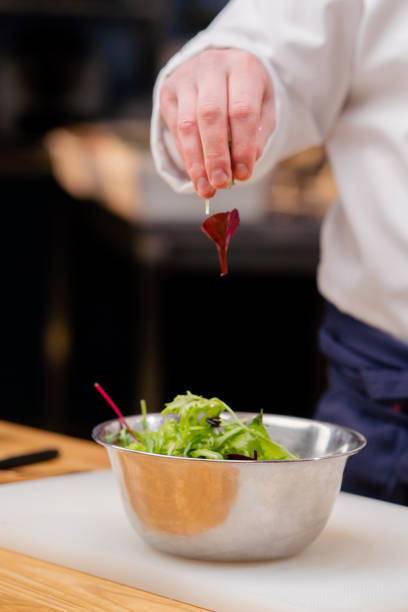 istock close-up of a chef's hand taking green salad from a large rectangular plate 2149223231