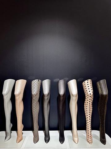 An ordered row of mannequin legs wearing a choice of stockings, on display in a shop