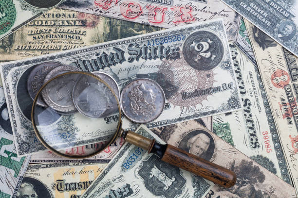 istock Old US banknotes and silver certificates with silver dollar coins and magnifying glass 2149223797