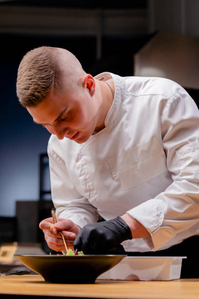 istock chef on a black plate in which there is salad the chef's hands lay out pieces beet with tweezers 2149224437
