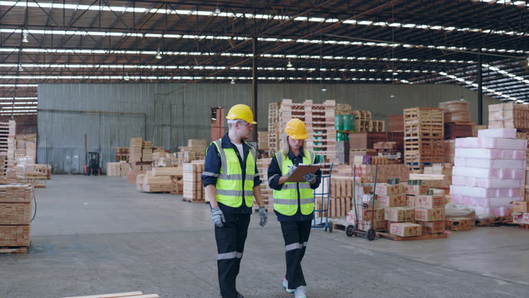 Team of industrial workers assessing lumber piles in a spacious warehouse.