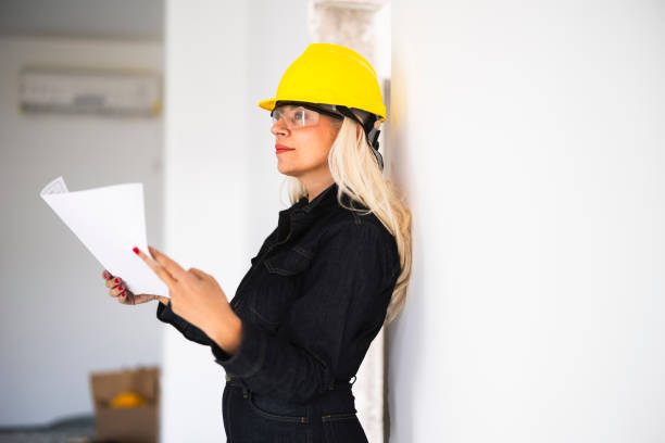 Female architect looking at blueprints on construction site