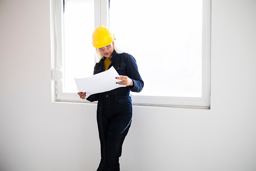 Female architect looking at blueprints on construction site