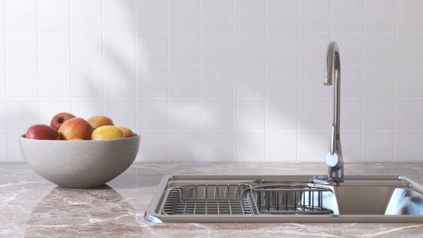 istock Marble kitchen table counter countertop, stainless sink, apple bowl in sunlight on square white tile wall 2149227564