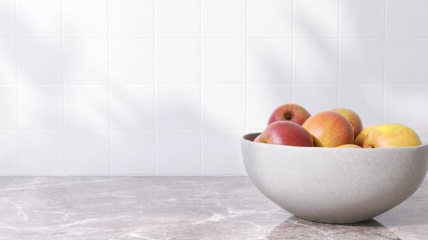 istock Brown marble kitchen table counter countertop with bowl of apple in sunlight on square white tile wall 2149227566