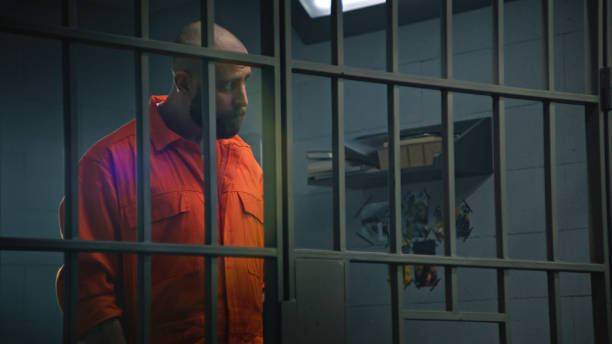 istock Prisoner in orange uniform talks with advocate and reads contract 2149233245