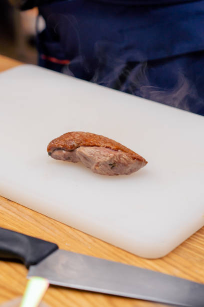 beautiful piece of fried duck breast steaming on a white board professional cooking