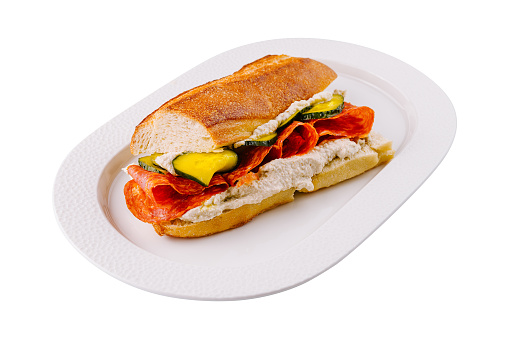 Appetizing pepperoni sandwich with fresh vegetables and mustard on a clean white plate, isolated on white