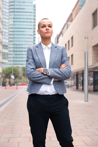Close-up of a caucasian businesswoman looking Thoughtful at the camera in a suit standing in outdoor workspace. Front view of a young lawyer with thoughtful expression staring