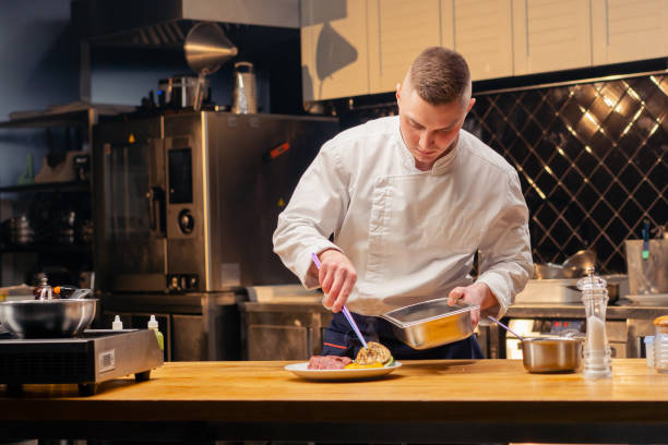 istock chef in the kitchen decorating with tweezers vegetables sliced beef steak medium rare on white plate 2149236417