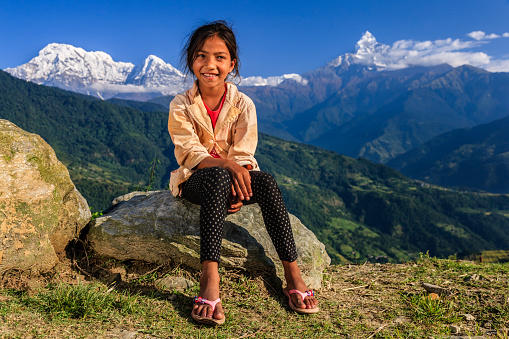 Happy Nepali little girl, Annapurna Range on background. The Annapurna region is in western Nepal where some of the most popular treks (Annapurna Sanctuary Trek, Annapurna Circuit) are located. Peaks in the Annapurnas include 8,091m Annapurna I, Nilgiri and Machhapuchchhre. The Annapurna peaks are among the world's most dangerous mountains to climb.
