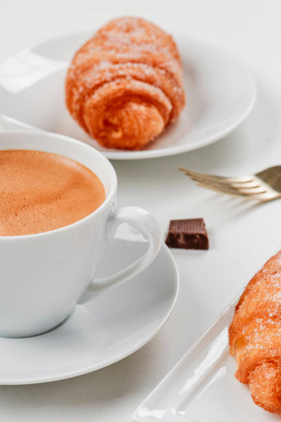 French breakfast, fresh croissants, black coffee, cream and butter on wooden table. Close-up.