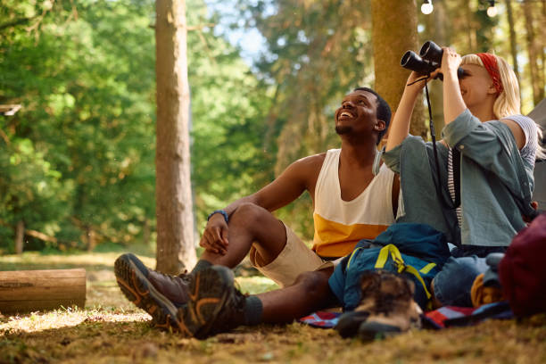 istock Happy couple of campers looking through binoculars while exploring the woods. 2149240099