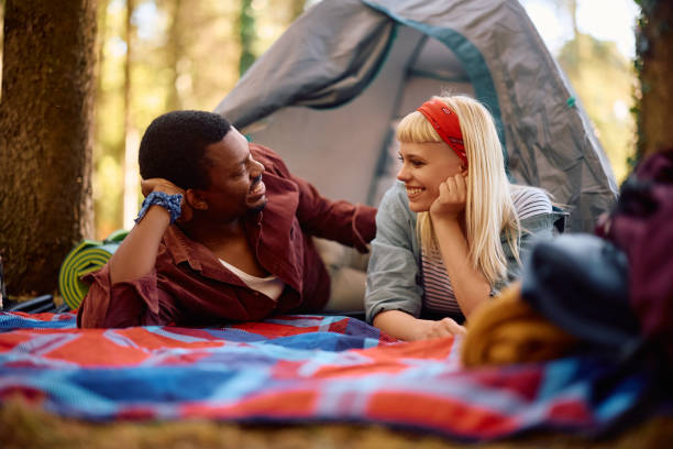 istock Young happy couple talking while relaxing by a tent on camping. 2149240113