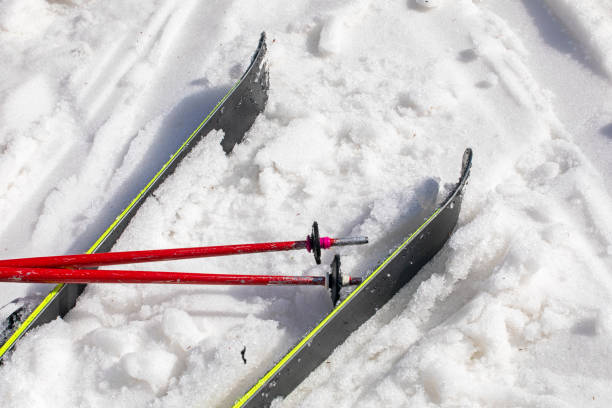 Macro shot highlighting modern alpine touring ski binding and boot interface, set against pristine snow and distant mountain peaks under clear blue skies.