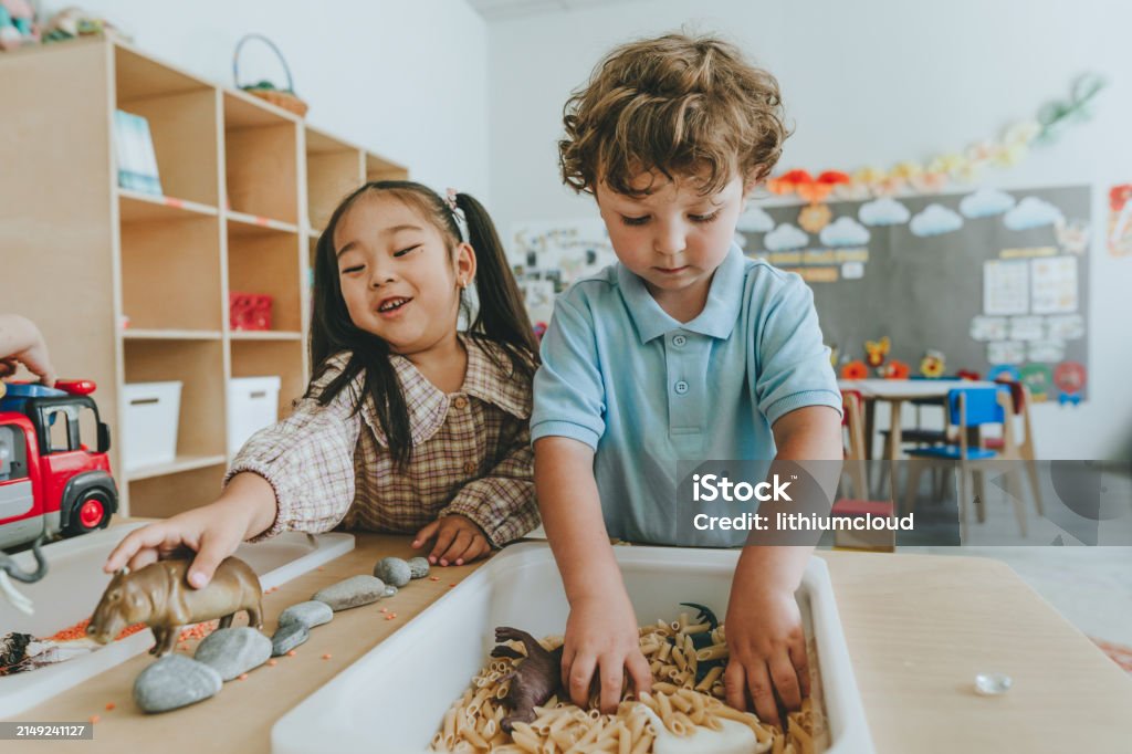 Children playing with toy figures in bulk cereals and pasta in kindergarten - Royaltyfri Barn Bildbanksbilder Children playing with toy figures in bulk cereals and pasta in kindergarten - Royaltyfri Barn Bildbanksbilder