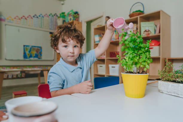 istock Boy watering a plant from a toy watering can in a kindergarten 2149241210