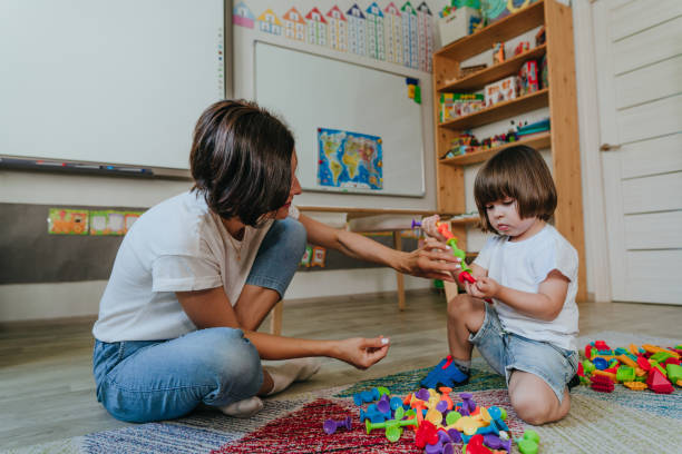 istock Young woman teacher playing with child in an educational constructor in a kindergarten 2149241378