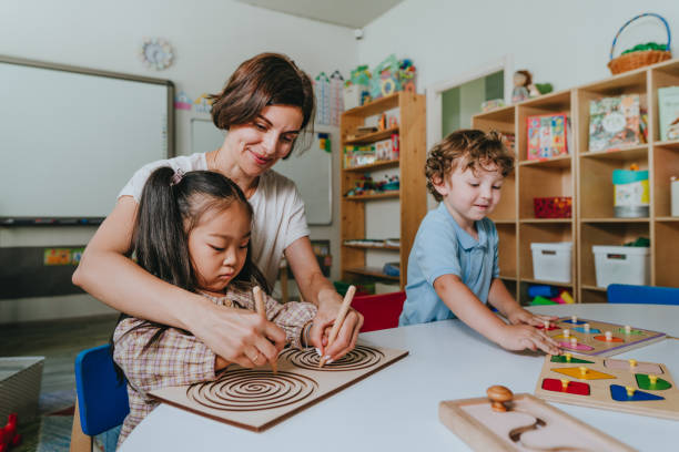 istock Children and teacher playing with educational wooden toys developing coordination with tabletop labyrinths in a kindergarten 2149241387