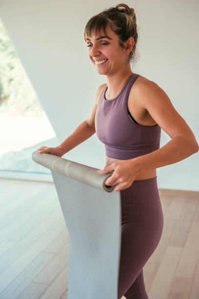 istock Young Woman Rolling Yoga Mat in Yoga Studio 2149242151