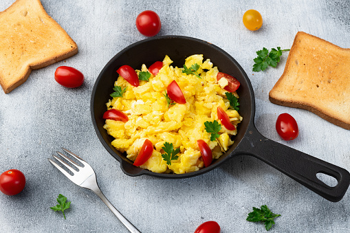 Healthy vegetarian breakfast . Scrambled eggs toast with cherry tomatoes and parsley . Top view