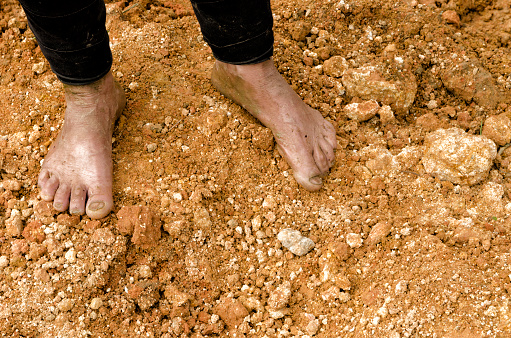 A person in rubber boots standing in the mud.