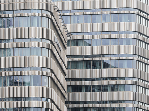 A very tall office building in Malmo, Sweden, stands prominently with a multitude of windows reflecting the sky. The architecture is modern and sleek, showcasing a blend of glass and concrete.