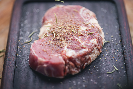 Roast Tenderloin beef fillet meat on a wooden board with herbs. Dark wooden background. Top view.