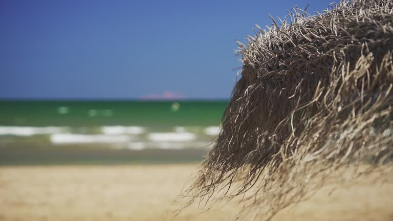 Close-up of a straw beach umbrella. Beach relaxation, beautiful sea. 4K