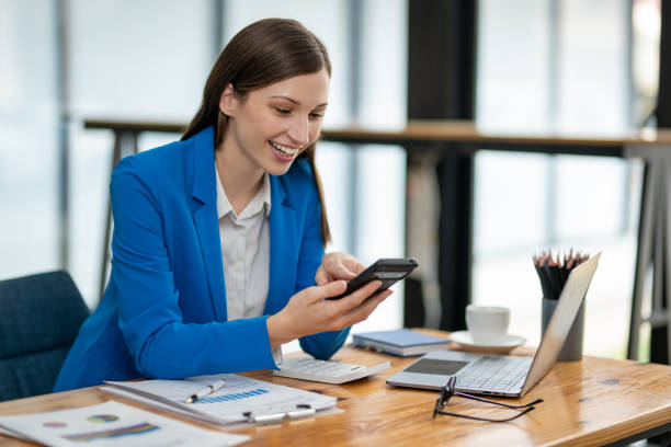 istock Young professional woman engaged in a phone conversation while working on her laptop at an organized office desk. 2149252793