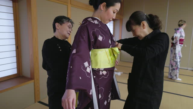 Female tourists getting kimono dressed in Japanese tatami room