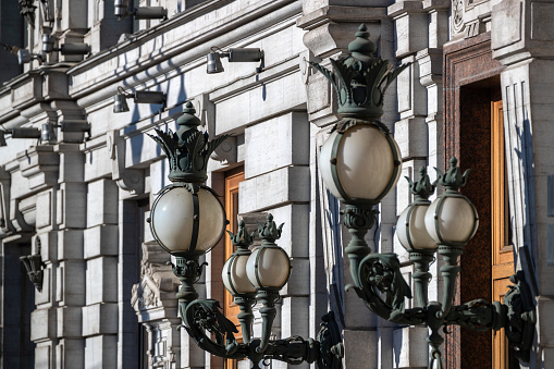 Art Nouveau style lamps on the facade of a historic building with security cameras.
